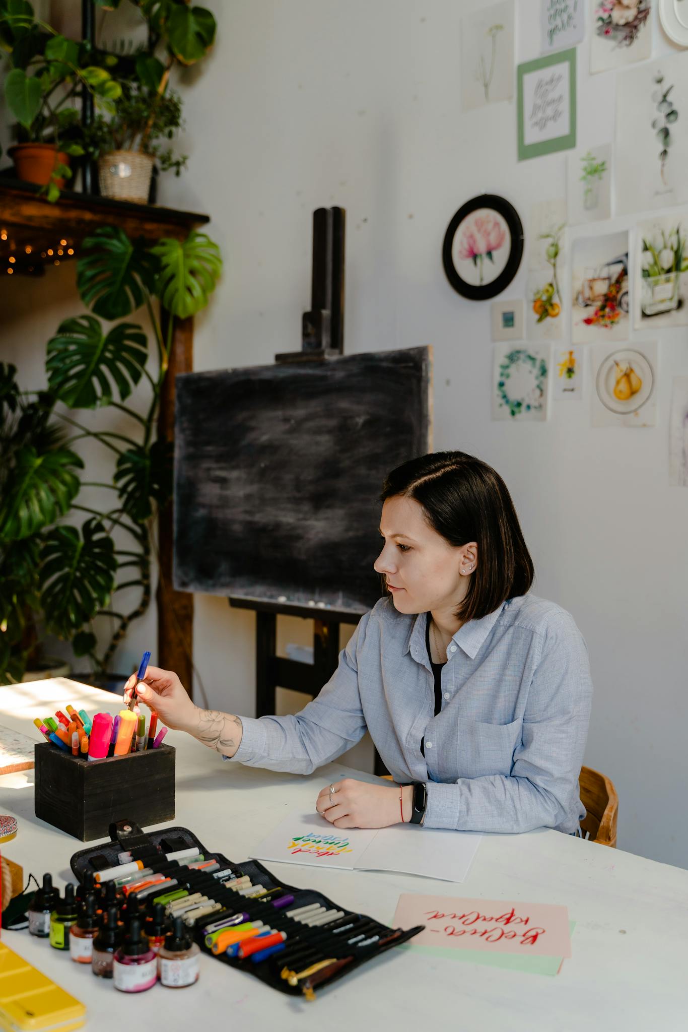 Artist in a creative studio engaged in sketching with various art supplies.