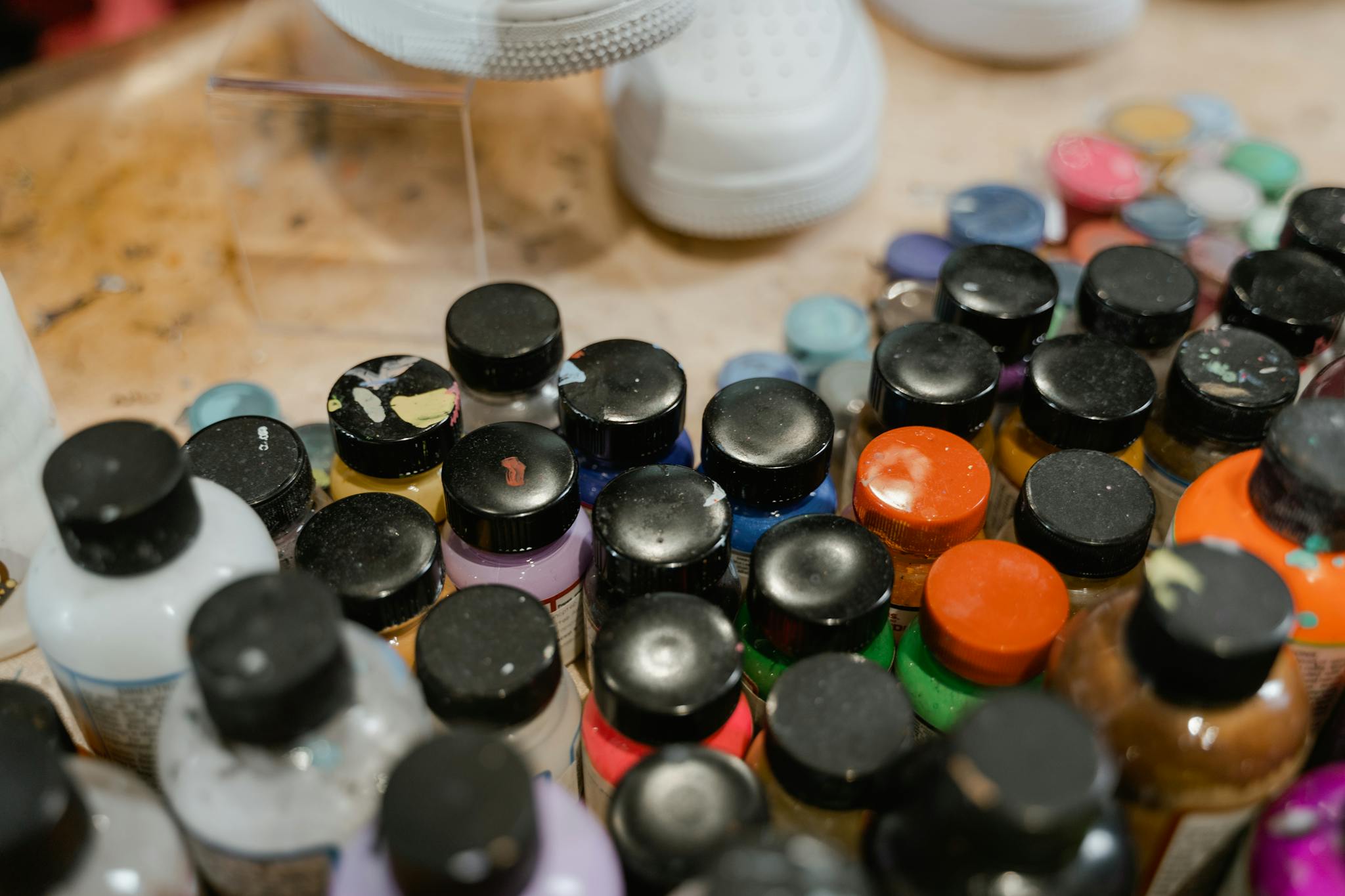Close-up of various paint bottles in an art studio setting, ideal for creative projects.